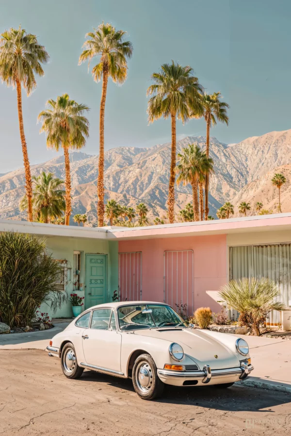 Porsche 911 classique blanche stationnée devant une maison Mid-Century Modern à Palm Springs avec des palmiers et les montagnes californiennes en arrière-plan.